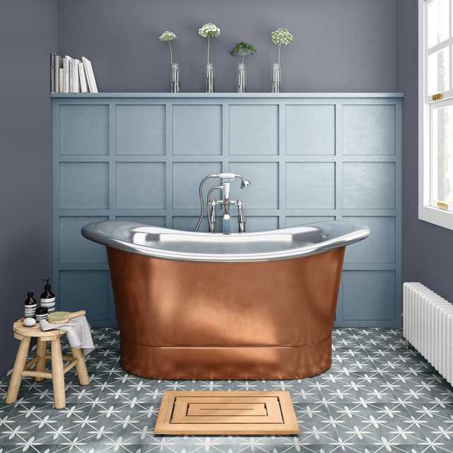 Copper bath in blue bathroom with panelled wall behind