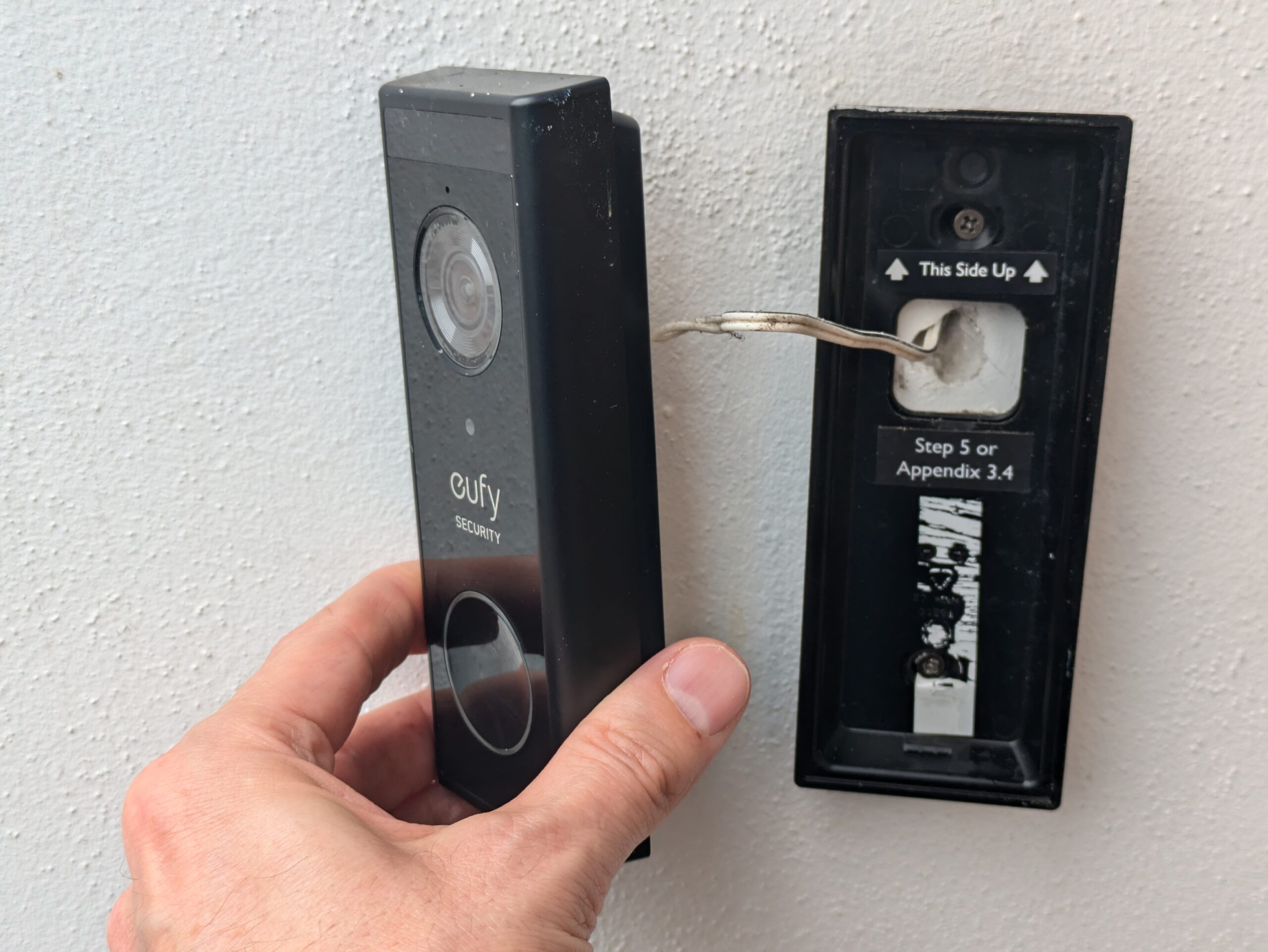 A smart doorbell removed from its mount, showing bell wire providing permanent power.