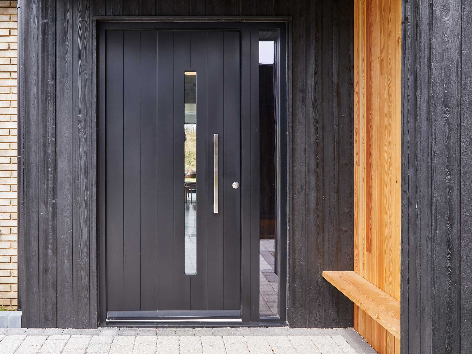 Adding seating to your porch will give it a practical purpose and somewhere to sit.Black wooden door with resting bench on the right