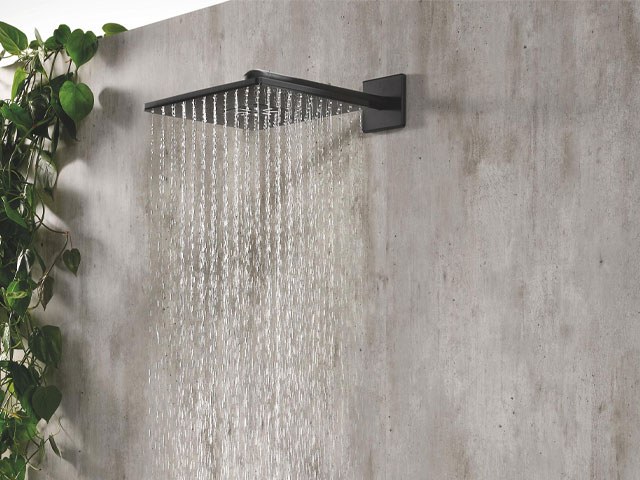 Close up of square black showerhead against microcement walls