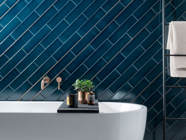 Glossy blue rectangular wall tiles behind a white freestanding bath 