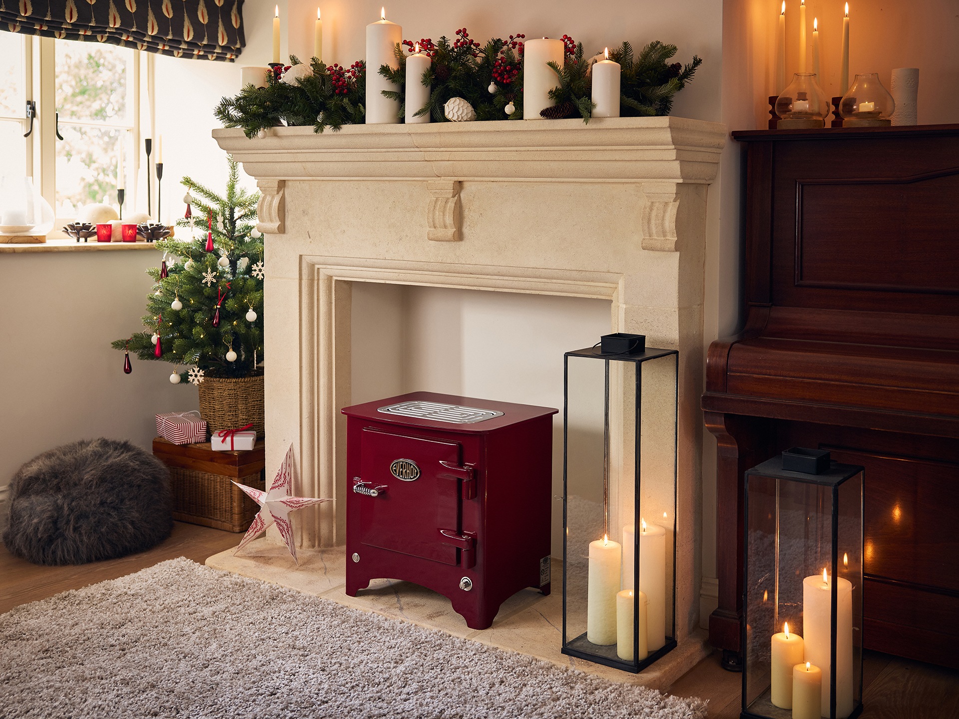 A red stove in a fireplace decorated for Christmas