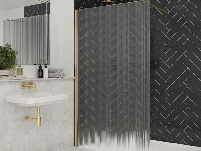 Walk-in shower in bathroom featuring fluted glass screen with gold-colour framing