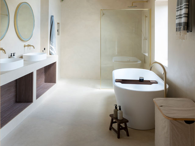 Bathroom with a twin basin vanity unit and a freestanding bath. The walls and floors are micro-cement in a neutral colour.