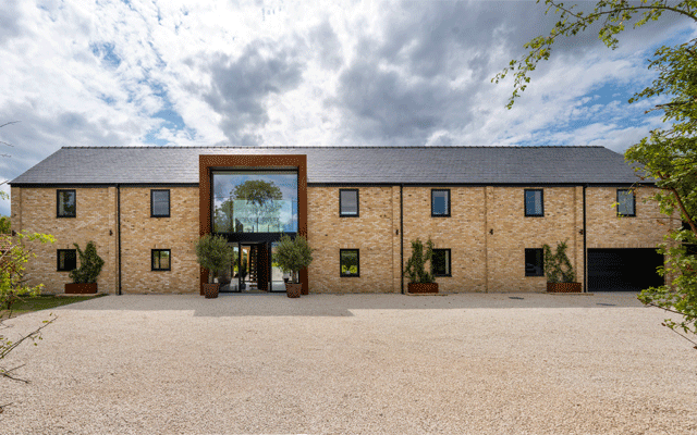 Looking over a gravel drive to the front exterior of a two-storey Grand Designs Lincolnshire Wolds house