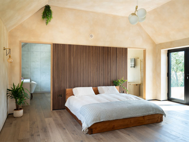 Bedroom with bed in the centre of the room behind which is a dressing area and en-suite bathroom