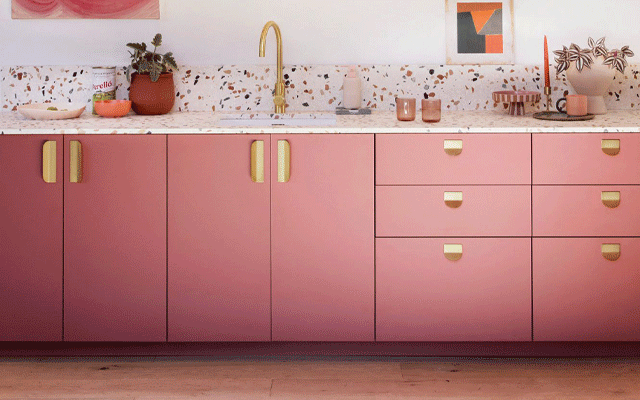 Single run of kitchen cabinets with fronts in pink and gold-colour handles