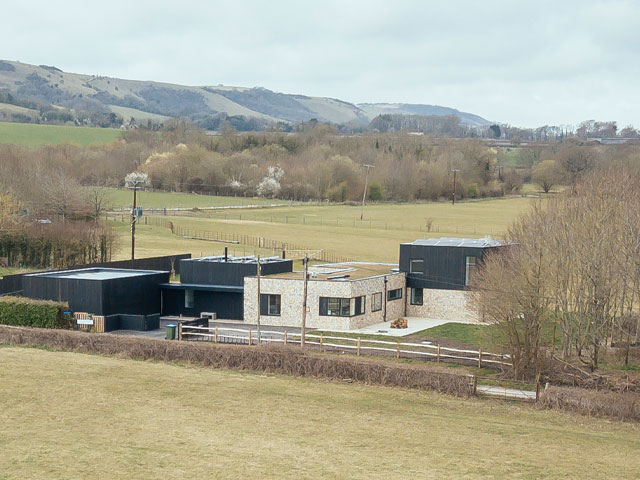 Distant overhead view of house in rolling countryside with solar panels on the roof