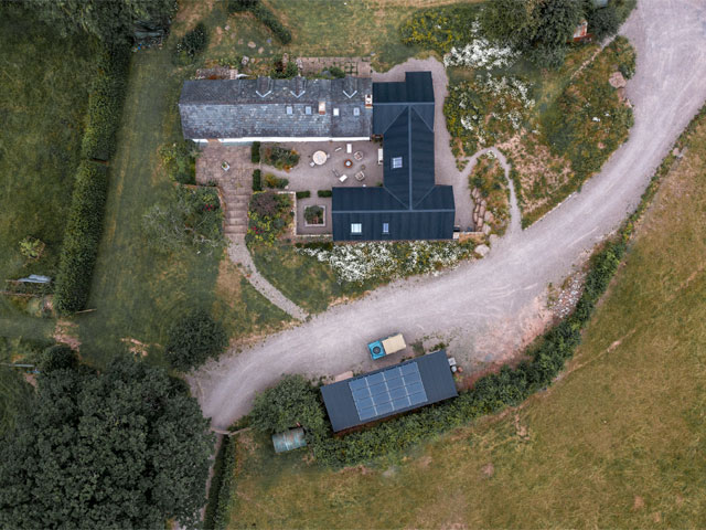 Overhead view of a longhouse and nearby outbuildings with solar panels on a barn roof