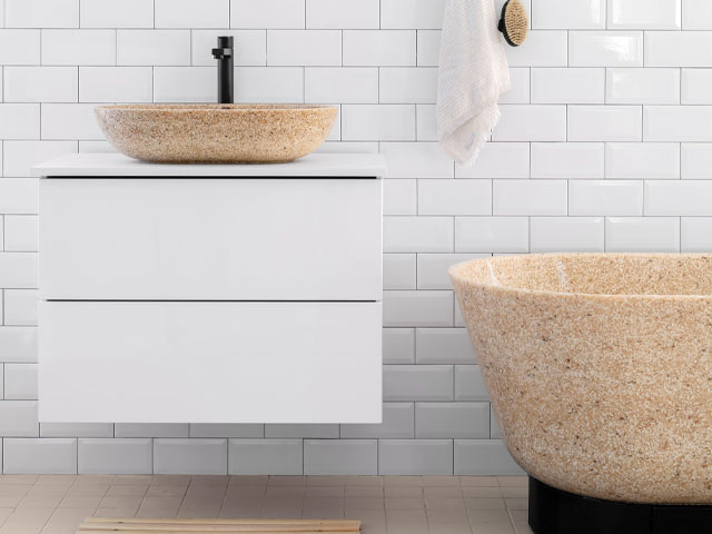 Bathroom with countertop basin on vanity unit and freestanding bath made from composite woodchip and resin material