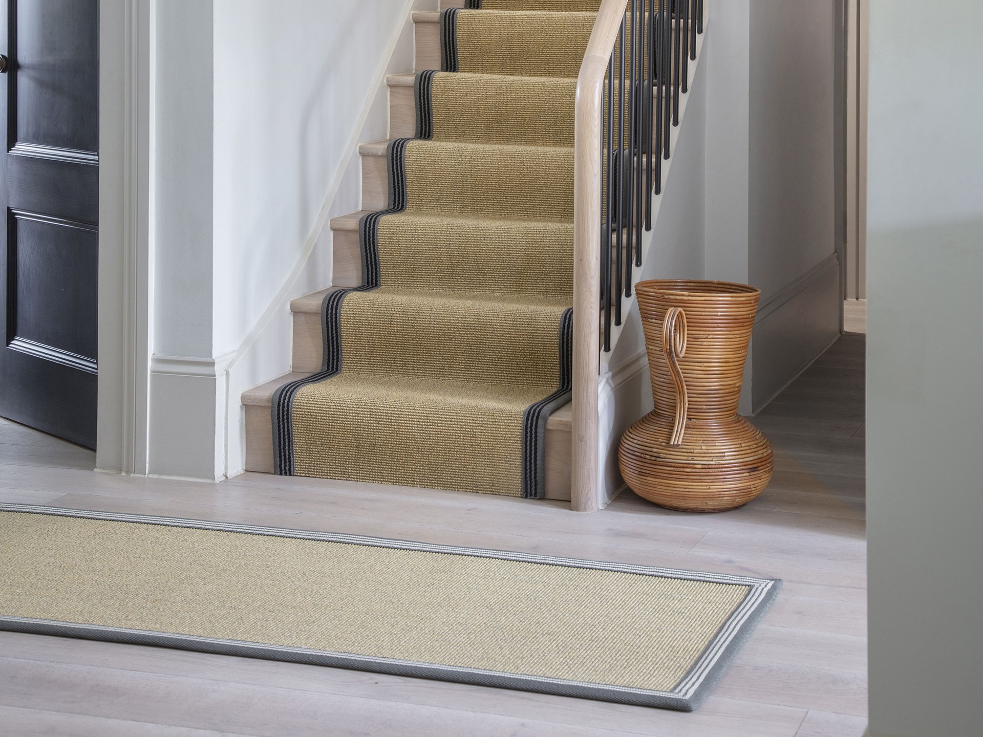 A hallway with a carpet on the stairs and runner on the floor