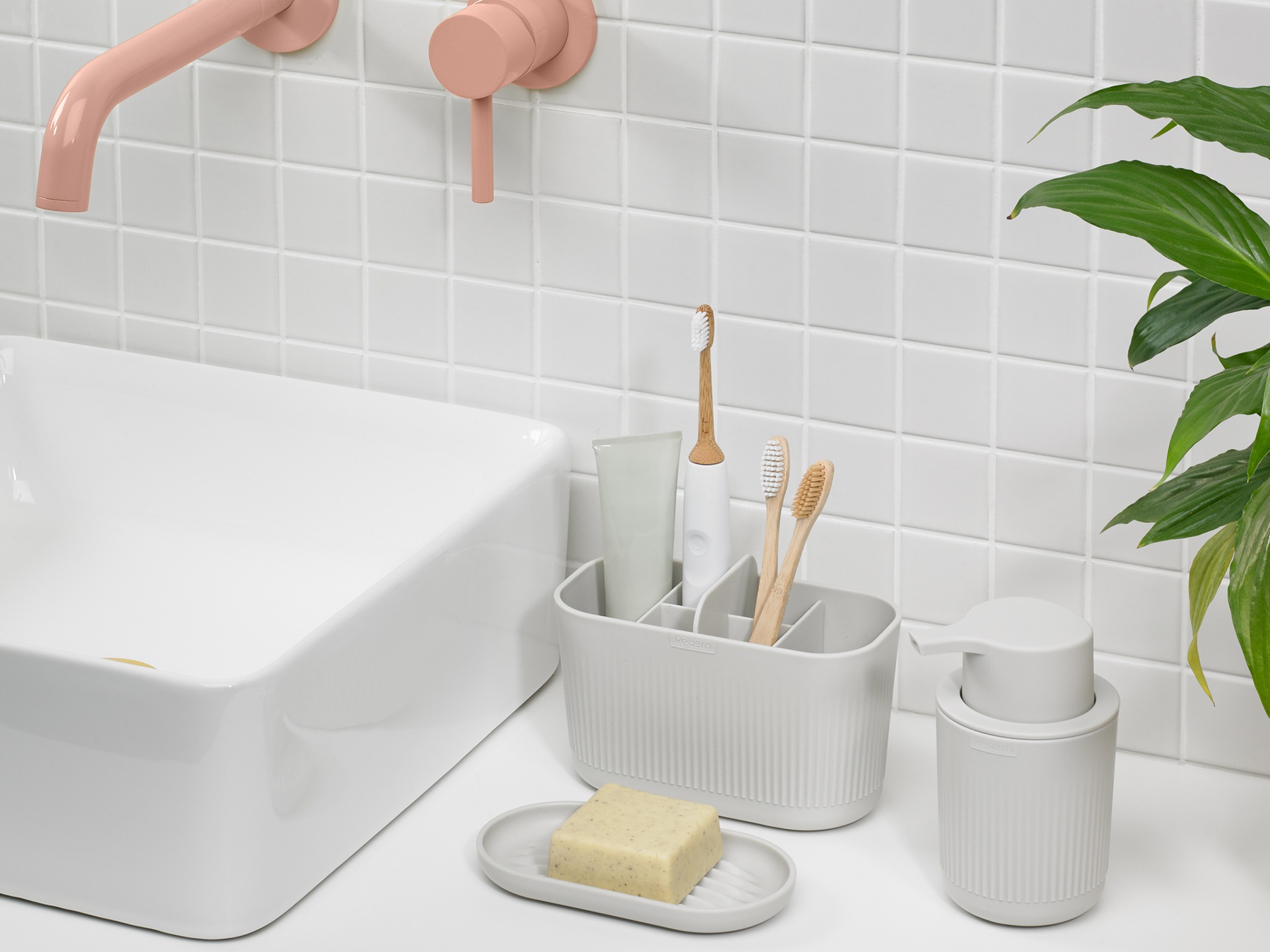 A toothbrush holder, soap dispenser and soap dish next to a sink