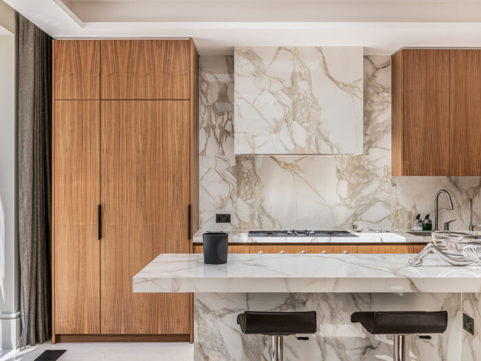 A minimalist kitchen with wooden cupboards and marble walls and island