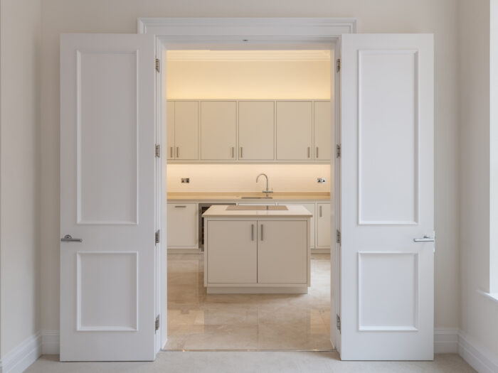  A white kitchen seen through a pair of double doors