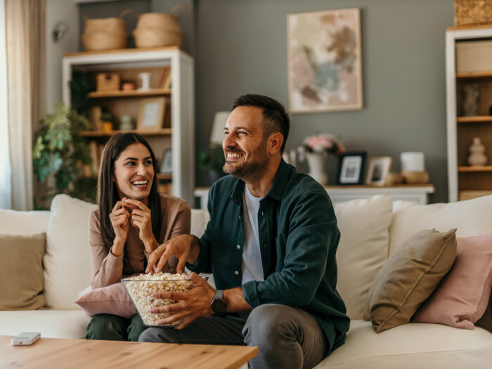 A hoppy couple eating popcorn on the sofa